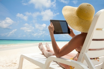 Woman having fun with her tablet by the sea