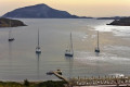 Sailing boats surrounding Cape Sounion at sunset