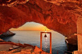 Sunset on the church of Agios Stefanos in Syros as seen through a cave