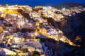 The brightly lit village of Oia spilling over the cliffs above the Aegean Sea