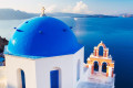 Blue-domed church in Oia with a view of the Santorinian caldera