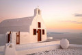 Sunset with a pink hue over a church in Oia, Santorini