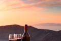 Wine bottle and glasses overlooking the caldera at sunset, Santorini island
