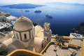 Church domes of unique architecture in the foreground and the volcanic deep blue bay in the backround, Santorini island