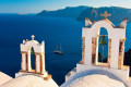 Church bell towers clashing with the deep blue sea surrounding Santorini