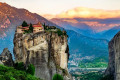 Sunrise in Meteora with a view of a Byzantine monastery sitting comfortably on a large rock pillar
