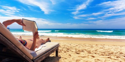 Woman relaxing and reading a book by the sea