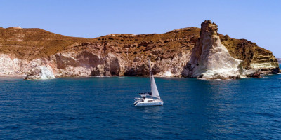 The catamaran sailing around the Santorinian coastline