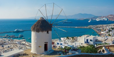 Old stone windmill backdropped by traditional buildings, Mykonos island