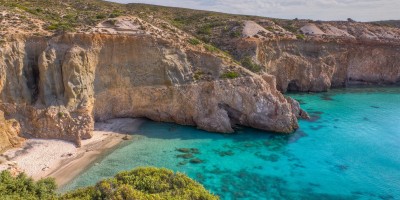 Tsigrado beach with turquoise waters against imposing golden rocks, Milos island