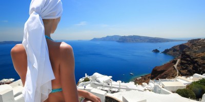 Woman enjoying the view of the caldera, the white houses and the infinite blue sea, Santorini island