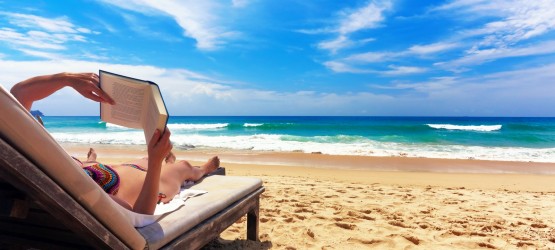 Woman relaxing and reading a book by the sea