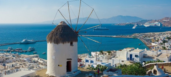 Old stone windmill backdropped by traditional buildings, Mykonos island