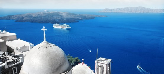 View of church dome and the vivid blue Aegean Sea encircling the volcanic caldera, Santorini island