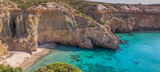 Tsigrado beach with turquoise waters against imposing golden rocks, Milos island